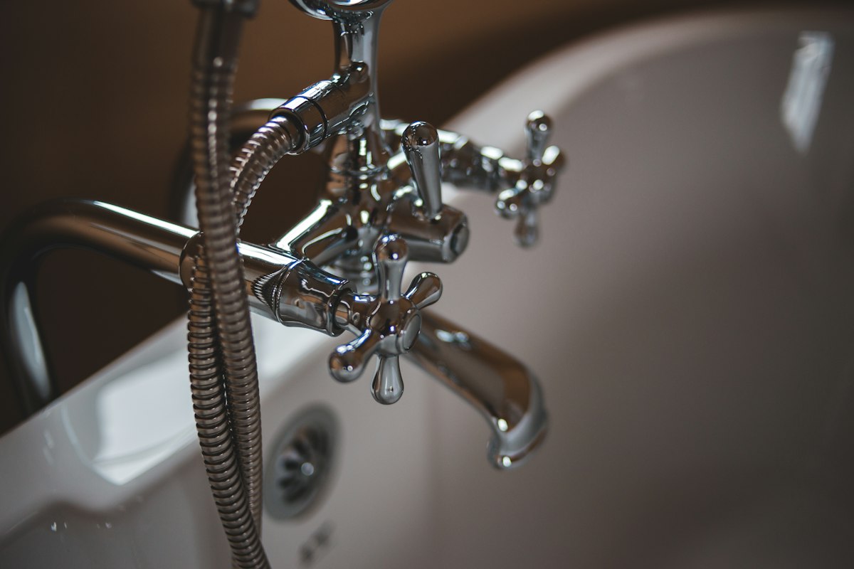 Professional plumber using a wrench to repair pipes under a kitchen sink