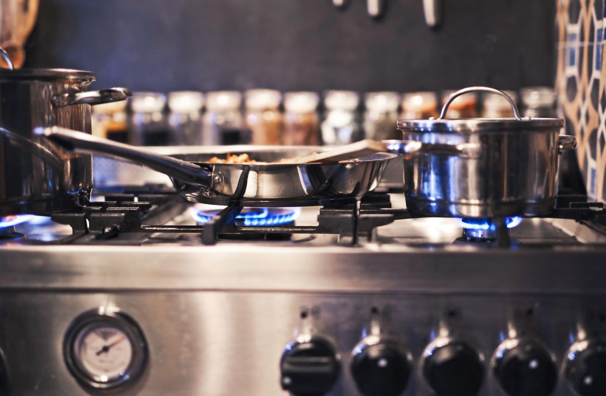 Stainless steel cooking pot on a gas stove with blue flames visible underneath